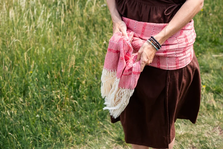 Doplňková brandová fotografie duly 
                        zavazující uzel na červeno-bílém šátku rebozo s třásněmi
                        